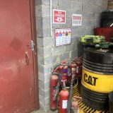“Row of different fire extinguishers lined up in a workshop, including water, foam, CO₂, and powder types — highlighting over-provision and potential confusion in an emergency.”