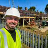 Health and safety consultant Ricky Nelson wearing a hard hat and high-visibility vest during an inspection at a scaffolded residential refurbishment site